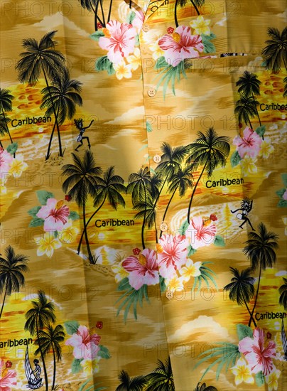 WEST INDIES, St Vincent And The Grenadines, Union Island, "Bright Yellow shirt with a pattern of coconut palm trees, flowers and the word Caribbean displayed for sale in Clifton"