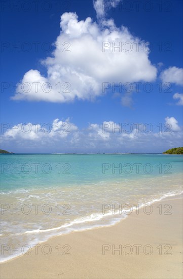 WEST INDIES, Grenada, Carriacou, Waves breaking on Paradise Beach at L'Esterre Bay with the turqoise sea and Sandy Island sand bar beyond.