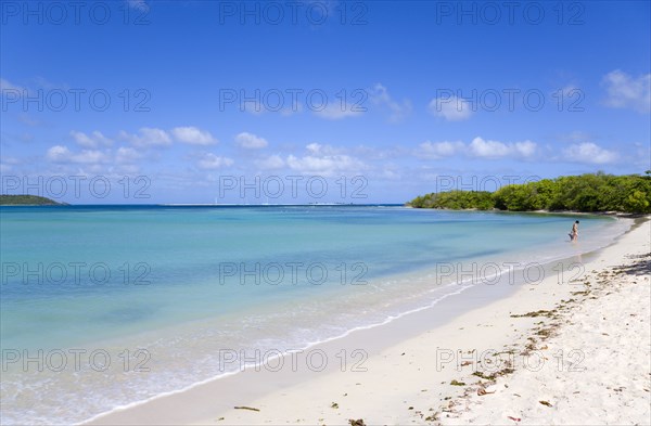 WEST INDIES, Grenada, Carriacou, Woman with toddler at the waters edge with gentle waves breaking on Paradise Beach at L'Esterre Bay with the turqoise sea and Point Cistern beyond.