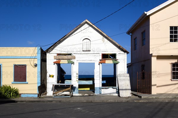 WEST INDIES, Grenada, Carriacou, Derelict building in the main street of Hillsborough with the harbour and sea visible through the empty building.