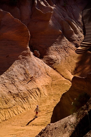 FRANCE, Provence Cote d’Azur, Le Sentier des Ocres (The Ochre Footpath) , "Small boy playing on sandy path through eroded, ochre landscape in the Belvedere Panorama area "