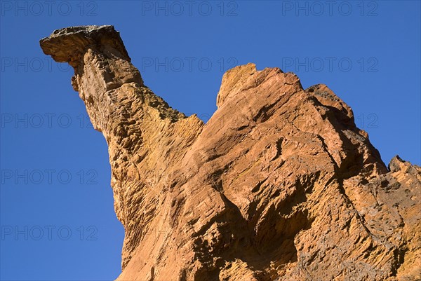 FRANCE, Provence Cote d’Azur, "Colorado Provencal.  Cheminee de Fee or Fairy Chimneys.  Angled view of a dramatic capped, ochre rock pinnacle against cloudless blue sky."