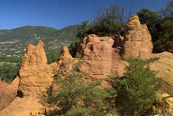 FRANCE, Provence Cote d’Azur, Colorado Provencal.  Cheminee de Fee or Fairy Chimneys.  Eroded ochre rock forms and surrounding landscape from viewpoint.