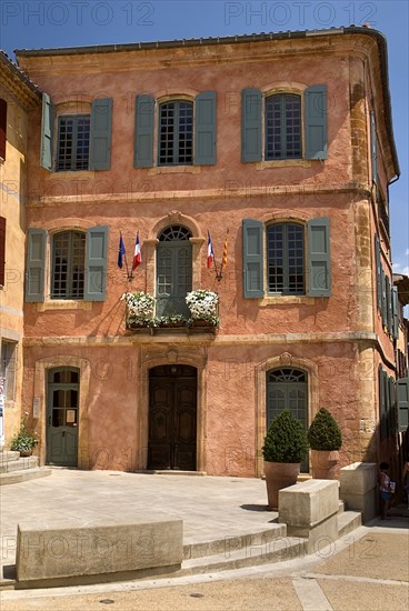 FRANCE, Provence Cote d’Azur, Vaucluse, Roussillon.  Exterior facade of building with typical ochre coloured walls and painted window shutters.