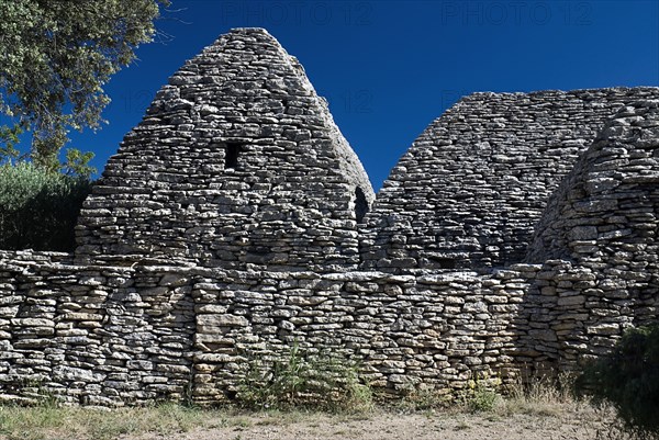 FRANCE, Provence Cote d’Azur, Vaucluse, "Le Village des Bories.  Primitive village comprising of mortarless, stone, beehive shaped huts or bories,each with a specific purpose.  Back of barn from Prov 137 with a dwelling house on the left."