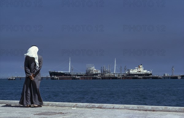 KUWAIT, Mina Ahmadi , Man wearing a white headscarf looking out across the sea towards the Mina Ahmadi oil terminal
