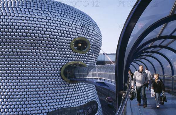 ENGLAND, West Midlands, Birmingham, "Selfridges Store at The Bullring Shopping Centre. Exterior detail of the spun aluminium discs and shoppers walking through The Parametric Bridge, a curved covered footbridge suspended over the street."