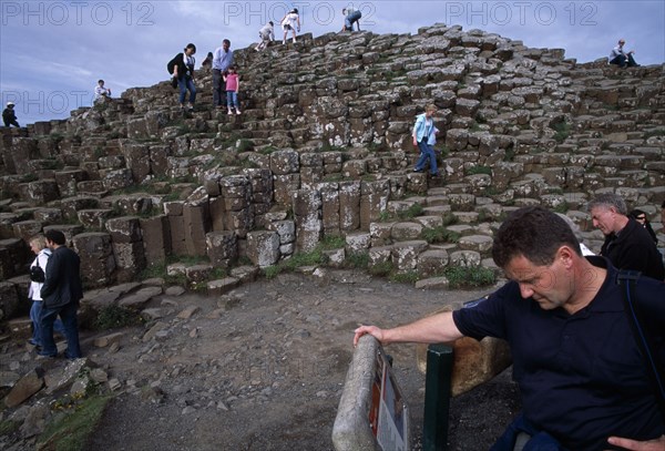 NORTHERN IRELAND, County Antrim, Giants Causeway, Visitors walking over the interlocking basalt stone columns left by volcanic eruptions.