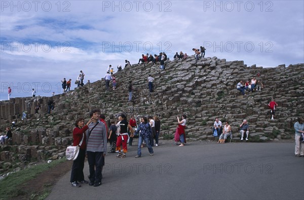 NORTHERN IRELAND, County Antrim, Giants Causeway, Visitors walking over the interlocking basalt stone columns left by volcanic eruptions.