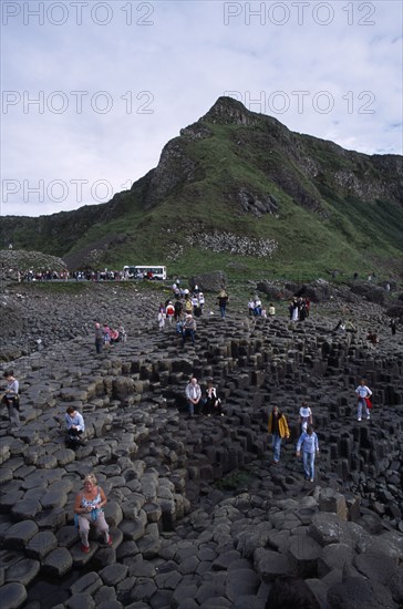 NORTHERN IRELAND, County Antrim, Giants Causeway, Visitors walking over the interlocking basalt stone columns left by volcanic eruptions.