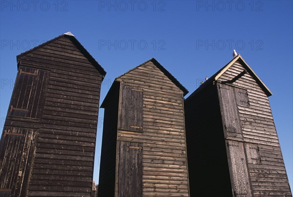 ENGLAND, East Sussex, Hastings, The Net Shops. Tall black wooden huts used for storing fishing nets.