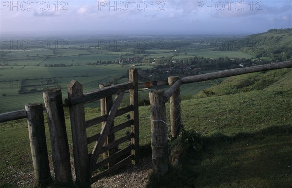 ENGLAND, West Sussex, Devils Dyke, Stile gate on Devil’s Dyke with view over lush green South Downs landscape