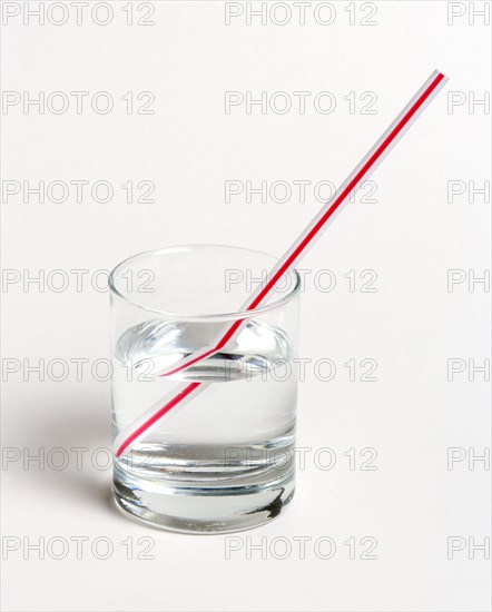 SCIENCE, Optics, Refraction, "A red and white straw in a glass of water on a white background. The straw appears to be broken, due to refraction of light as it emerges into the ai"