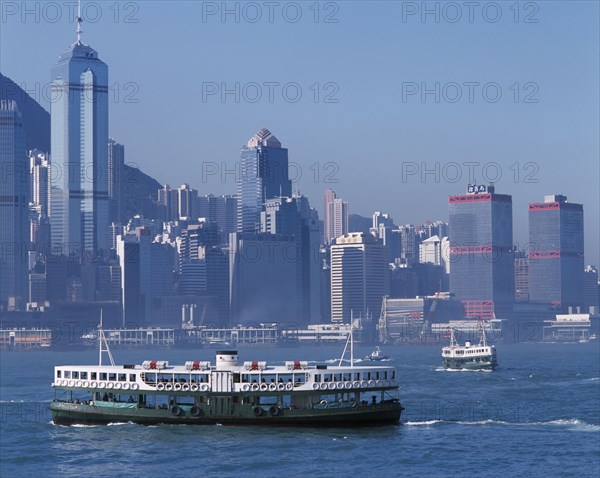 CHINA, Hong Kong, Victoria Harbour, Star Ferries crossing Victoria Harbour with high rise buildings on city skyline beyond.