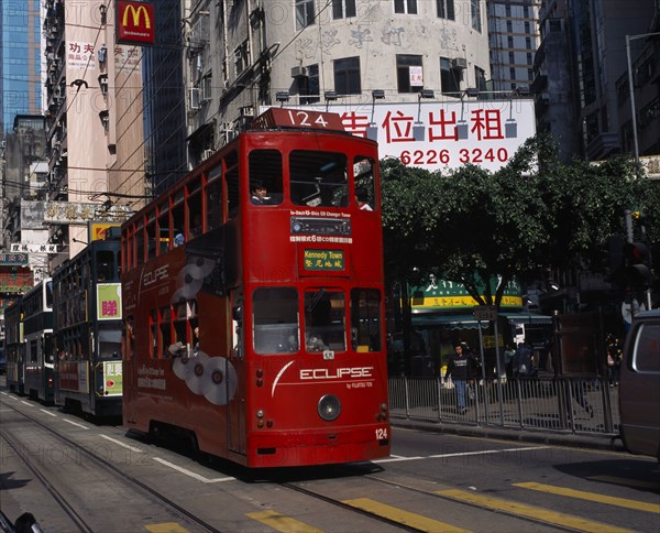 CHINA, Hong Kong, Hong kong Island trams on city street with high rise buildings and advertising hoardings and McDonalds sign overhead.