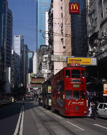 CHINA, Hong Kong, Hong kong Island trams on city street with high rise buildings and advertising hoardings and McDonalds sign overhead.