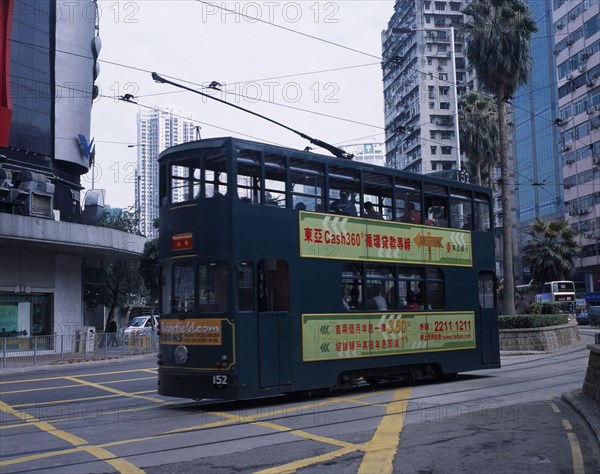CHINA, Hong Kong, Hong kong Island tram with advertising printed along side and high rise buildings behind.