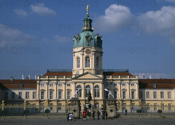 GERMANY, Berlin, Charlottenburg Palace.  Exterior facade of eighteenth century baroque palace with visitors outside ironwork gates.