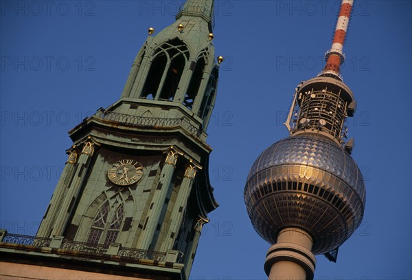GERMANY, Berlin, Angled detail of the Fernsehturm or television tower beside clock and bell tower of historic St Mary s Church also called Marienkirche.