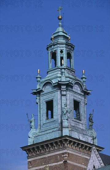 POLAND, Krakow, Detail of church clock tower of Wawel Cathedral with statues positioned at four corners of base.