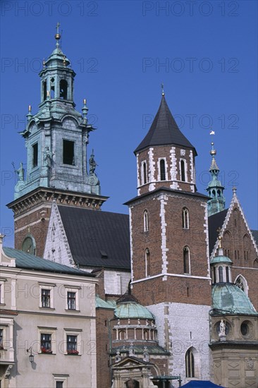 POLAND, Krakow, Detail of Wawel Cathedral exterior with clock tower above second tower and series of domed and pointed rooftops.