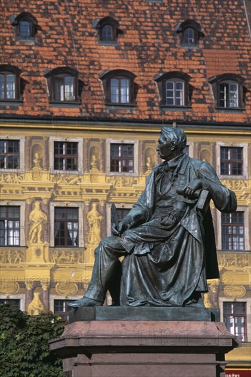 POLAND, Wroclaw, Detail of building facade with tromp l oeil painted mural.  Seated statue of writer Alexander Fredo in foreground.