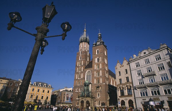 POLAND, Krakow, Mariacki Basilica or Church of St Mary.  Gothic  red brick exterior built in the fourteenth century overlooking the main market square with street lamp in foreground.