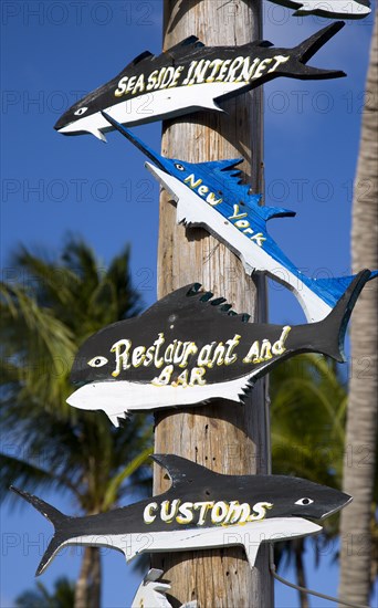 WEST INDIES, St Vincent And The Grenadines, Union Island, "Wooden signs in the shape of different fish on a post at The Anchorage Yacht Club in Clifton Harbour pointing to the internet cafe, restaurant and customs"