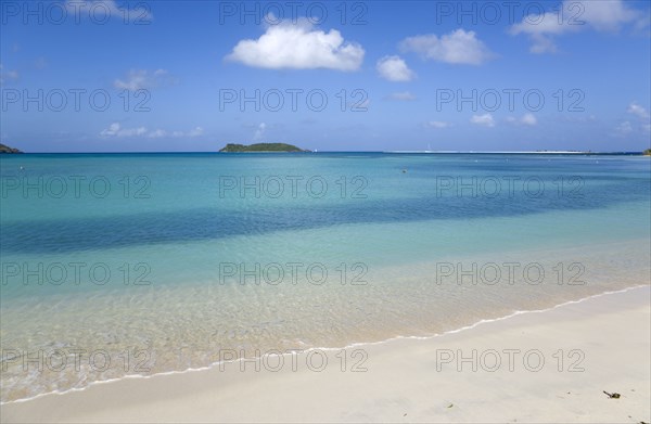 WEST INDIES, Grenada, Carriacou, The calm clear blue water breaking on Paradise Beach in L'Esterre Bay with Sandy Island in the distance