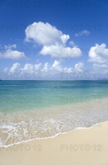 WEST INDIES, Grenada, Carriacou, The calm clear blue water breaking on Paradise Beach in L'Esterre Bay with Sandy Island in the distance