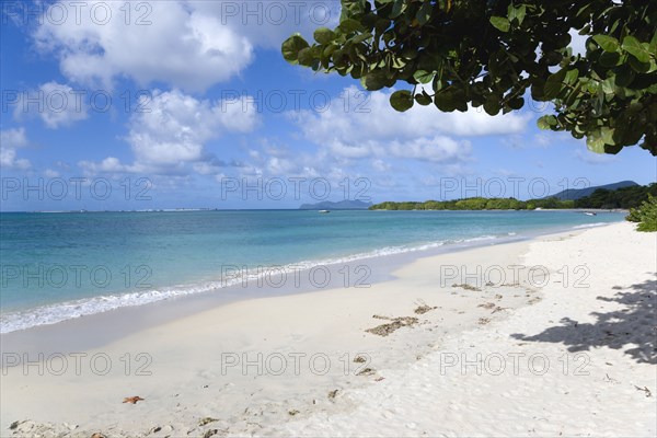 WEST INDIES, Grenada, Carriacou, The calm clear blue water breaking on Paradise Beach in L'Esterre Bay with Sandy Island and Petite Martinique in the distance