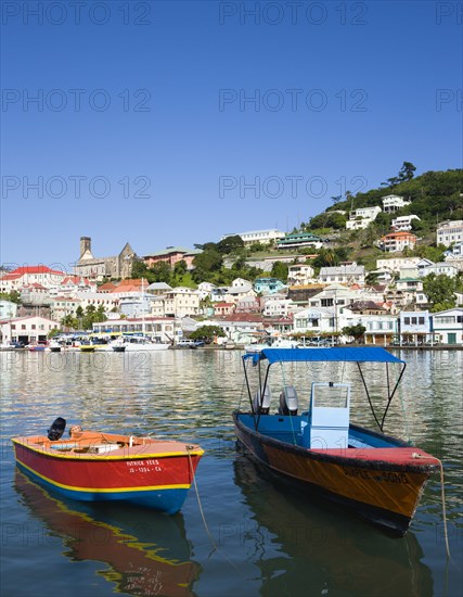 WEST INDIES, Grenada, St George, Water taxi boats moored in the Carenage harbour of the capital city of St George's with houses and the roofless cathedral damaged in Hurricane Ivan on the nearby hill
