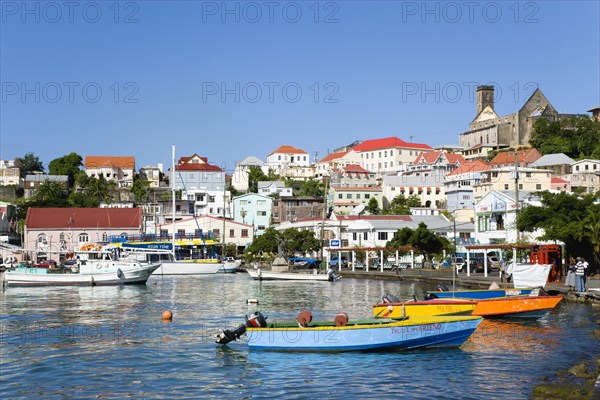 WEST INDIES, Grenada, St George, Water taxi boats moored in the Carenage harbour of the capital city of St George's with houses and the roofless cathedral damaged in Hurricane Ivan on the nearby hill