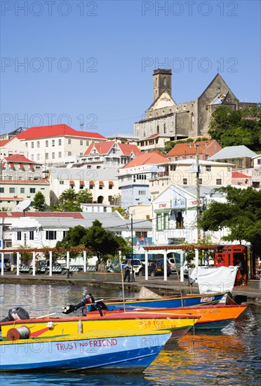 WEST INDIES, Grenada, St George, Water taxi boats moored in the Carenage harbour of the capital city of St George's with houses and the roofless cathedral damaged in Hurrican Ivan on the nearby hill