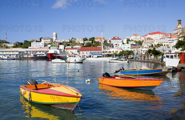 WEST INDIES, Grenada, St George, Water taxi boats moored in the Carenage harbour of the capital city of St George's with houses and the roofless cathedral damaged in Hurrican Ivan on the nearby hill