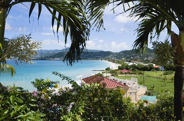 WEST INDIES, Grenada, St George, Gentle waves of the aquamarine sea breaking on the two mile stretch of the white sand Grand Anse Beach seen through palm trees