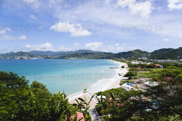 WEST INDIES, Grenada, St George, Gentle waves of the aquamarine sea breaking on the two mile stretch of the white sand Grand Anse Beach with the capital city of St George's in the distance