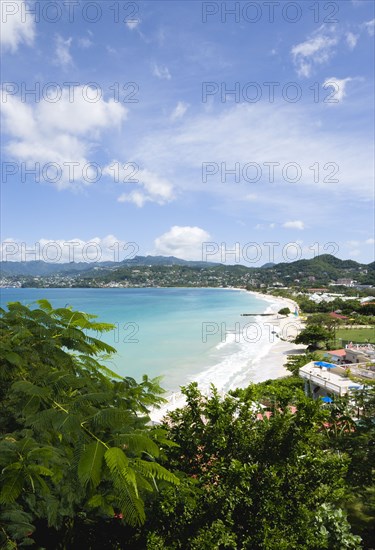 WEST INDIES, Grenada, St George, Gentle waves of the aquamarine sea breaking on the two mile stretch of the white sand Grand Anse Beach with the capital city of St George's in the distance