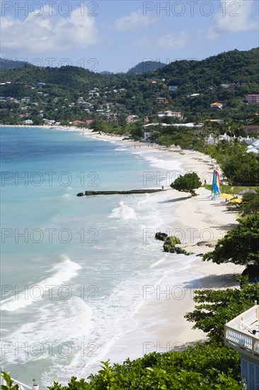 WEST INDIES, Grenada, St George, Waves of the aquamarine sea breaking on the two mile stretch of Grand Anse Beach with people on the white sandy beach