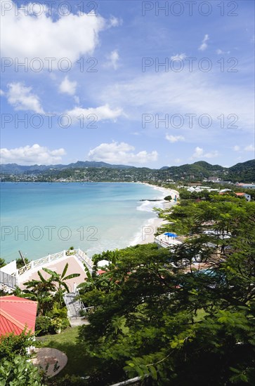 WEST INDIES, Grenada, St George, Waves of the aquamarine sea breaking on the two mile stretch of the white sandy Grand Anse Beach with the capital city of St George's in the distance