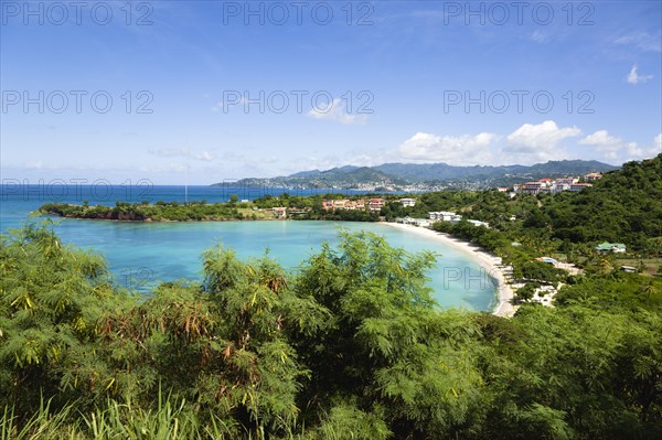 WEST INDIES, Grenada, St George, The aquamarine sea and tree lined white sand of BBC Beach in Morne Rouge Bay with the capital city of St George's in the distance