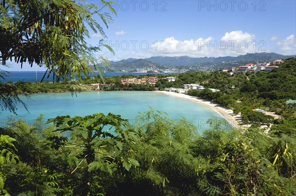 WEST INDIES, Grenada, St George, The aquamarine sea and tree lined white sand of BBC Beach in Morne Rouge Bay with the capital city of St George's in the distance