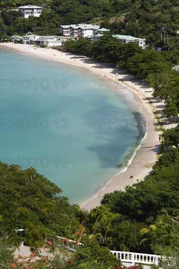 WEST INDIES, Grenada, St George, The aquamarine sea and tree lined white sand of BBC Beach in Morne Rouge Bay with tourists walking on the beach