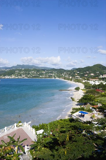 WEST INDIES, Grenada, St George, Waves of the aquamarine sea breaking on the two mile stretch of Grand Anse Beach with people on the white sandy beach