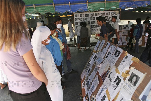 THAILAND, Phang Nga District, Takua PA, "Tsunami. Thai's and foreigners look at the pictures of the unidentifeid dead posted up outside the a temple, wat Yan Yao, 130kms north of Phuket on the 2nd Jan."