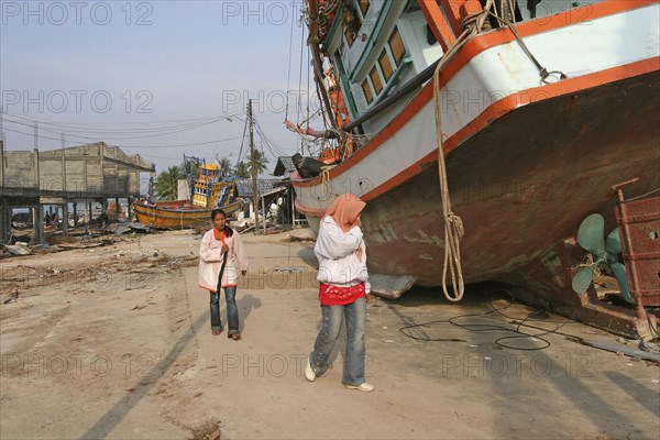 THAILAND, Phang Nga District, Nam Khem, "Tsunami. People walk past boats that have been pushed onto the streets in the village, nothing is left standing in. 2500 people are pressumed dead. 125kms north of Phuket on the 2nd Jan."