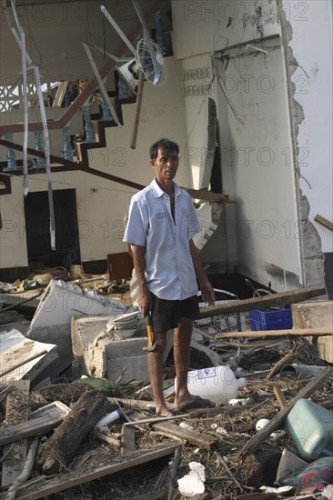THAILAND, Phang Nga District, Nam Khem, "Tsunami. A man stands outside of what is left of his house and tries to salvage what he can from the damage caused by the tsunami, nothing is left standing in the village. 2500 people are pressumed dead 125kms north of Phuket on the 2nd Jan"