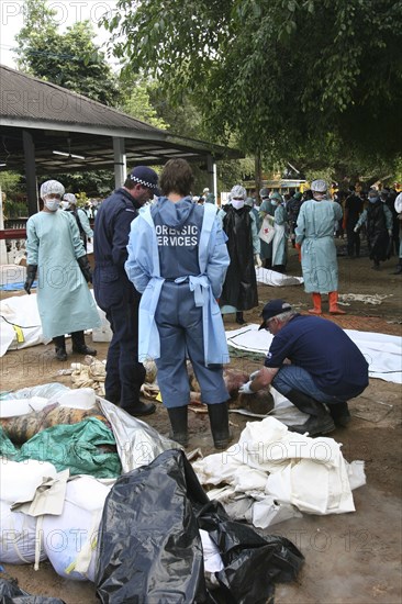 THAILAND, Phang Nga District, Takua PA, "Tsunami. Australian forensic team. Volunteers try to cool off victims of Tsunami with dry ice blocks in the outdoor morgue where 100's of corpses are being stored without refridgeration , awaiting DNA identification. At a temple wat Yan Yao 130kms north of Phuket on the 31st Dec."