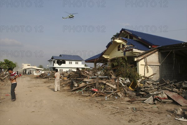 THAILAND, Phang Nga District, Nam Khem, "Tsunami. Locals look up at a helicopter which is surveying the damage caused by the tsunami, nothing is left standing in the village 2500 people are pressumed dead 125kms north of Phuket on the 2nd Jan."