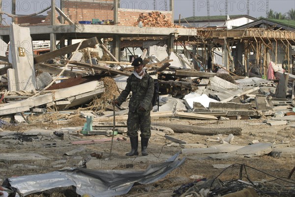 THAILAND, Phang Nga District, Nam Khem, "Tsunami. Thai Army soldiers who has been helping in the clean up at the devestated village caused by the tsunami also look for any bodies, nothing is left standing in the village. 2500 people are pressumed dead. 125kms north of Phuket on the 2nd Jan."